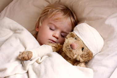 Sleeping boy with bandaged teddy bear