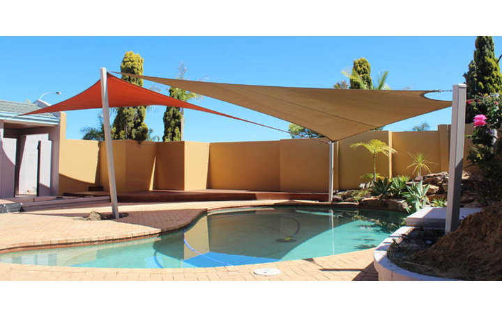 Photograph of 2, 4 sided sails over pool. 4 Posts in total plus a wall mount. The sails share 2 posts. Fabric is Rainbow Desert Sands and Terracotta.